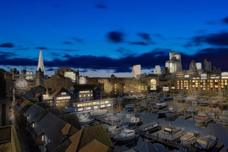Evening cityscape view with illuminated buildings, waterfront, boats, and blue twilight sky