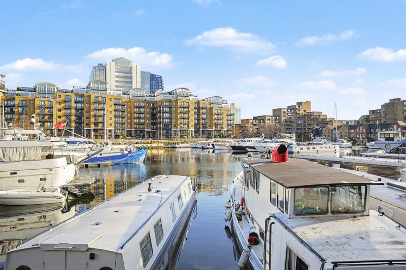 Waterfront view with moored boats and yellow apartment buildings under blue sky