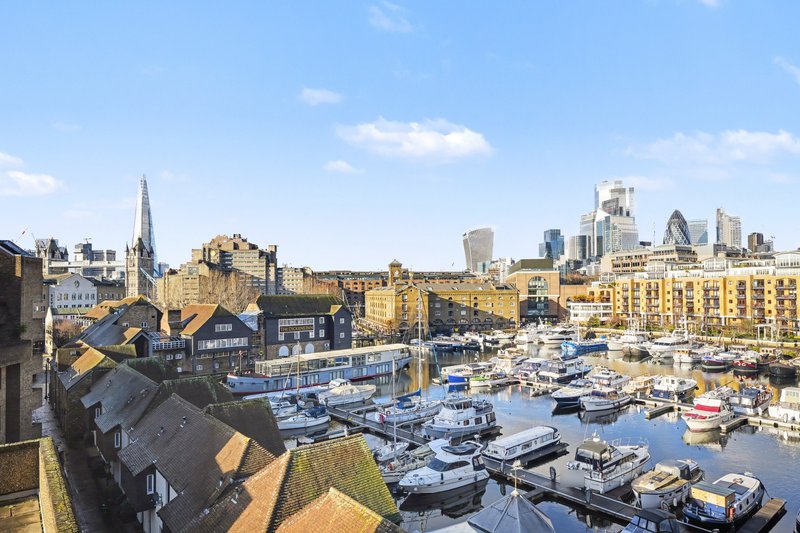 Waterfront marina with moored boats, historic buildings, and city skyline in background