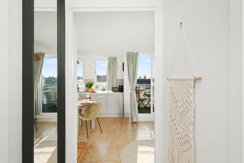 Bright apartment interior with open-plan living area, cork flooring, large windows and city views