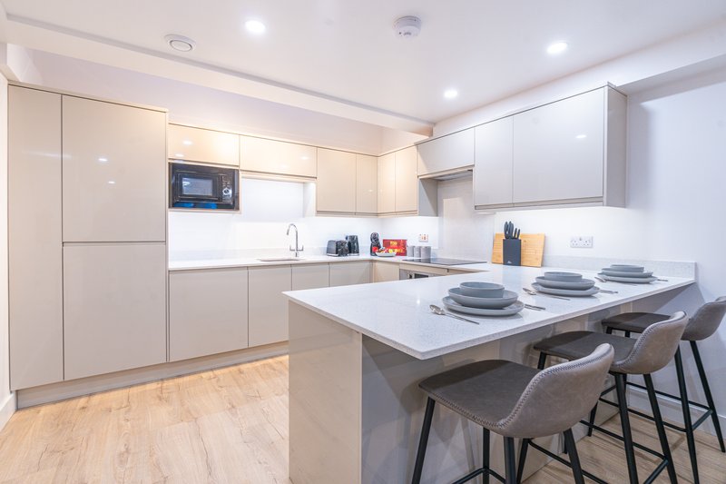 Modern kitchen with white cabinetry, island seating, stainless steel appliances and wooden flooring