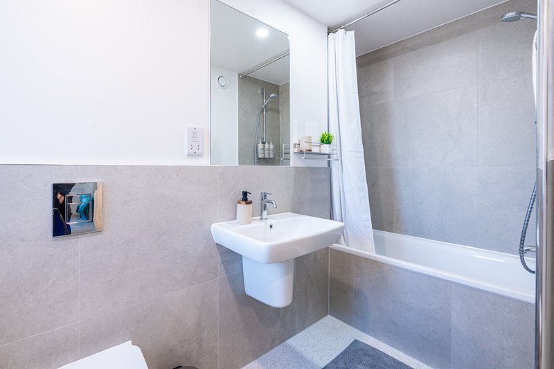 Modern bathroom with wall-mounted sink, mirror, bathtub and shower enclosure