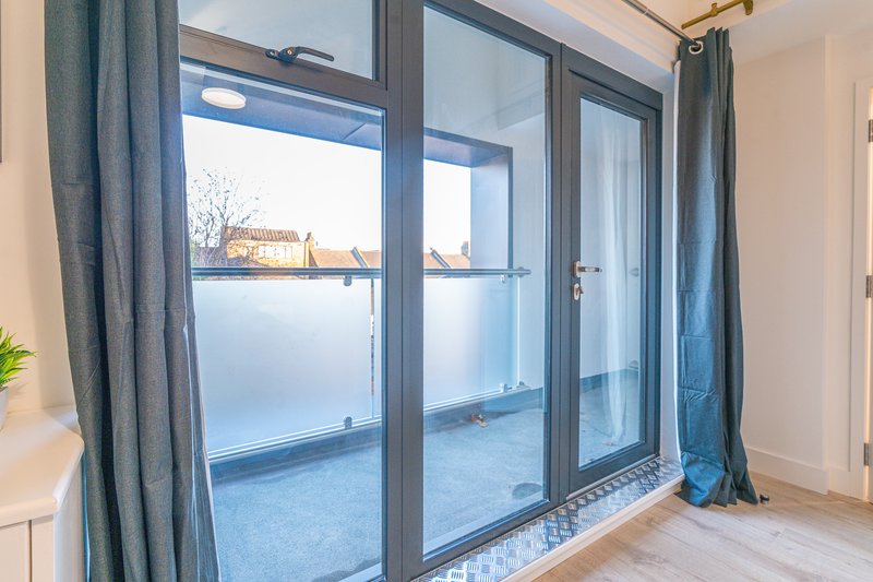 Bright modern bedroom with glass sliding doors opening onto a balcony with city views
