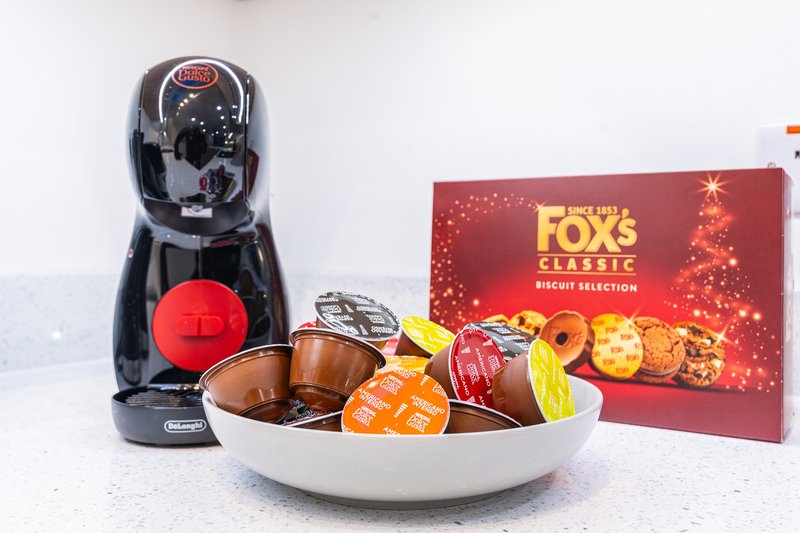 Kitchen counter with coffee machine, bowl of biscuits and confectionery, branded packaging