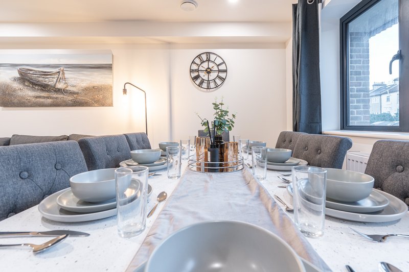 Modern dining room with marble table, place settings, blue upholstered chairs and clock