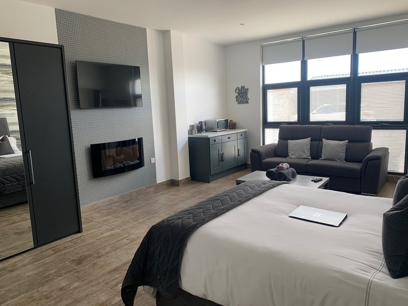 Modern bedroom with double bed, fireplace, TV, sofa seating area and large windows