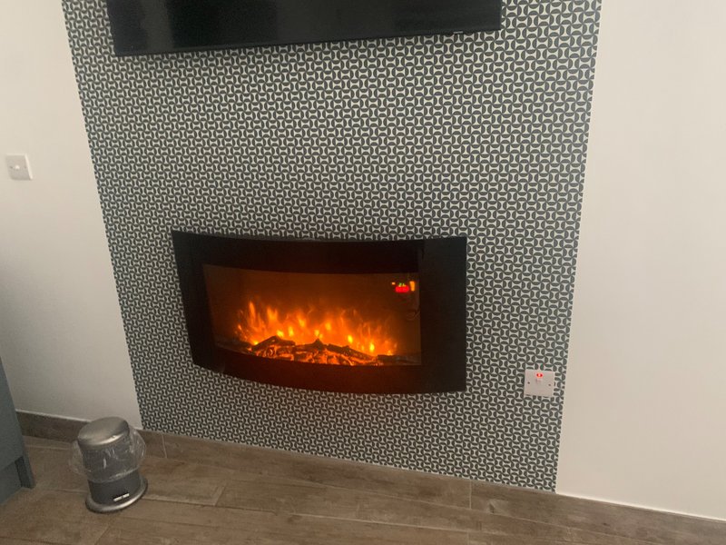 Modern fireplace with textured tiled surround and wall-mounted electric fire unit