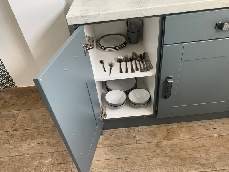 Kitchen drawer open showing organized cutlery, plates, and tableware storage