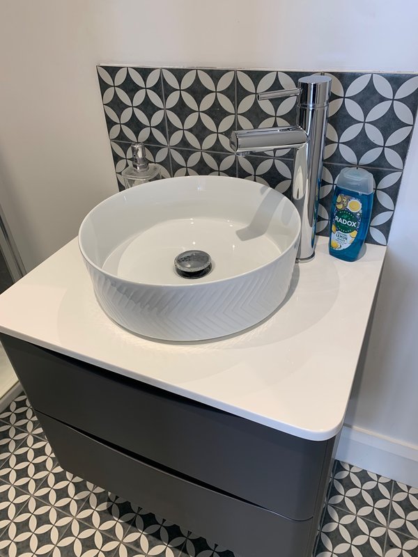 Modern bathroom sink with white ceramic basin, chrome faucet and patterned tile backsplash