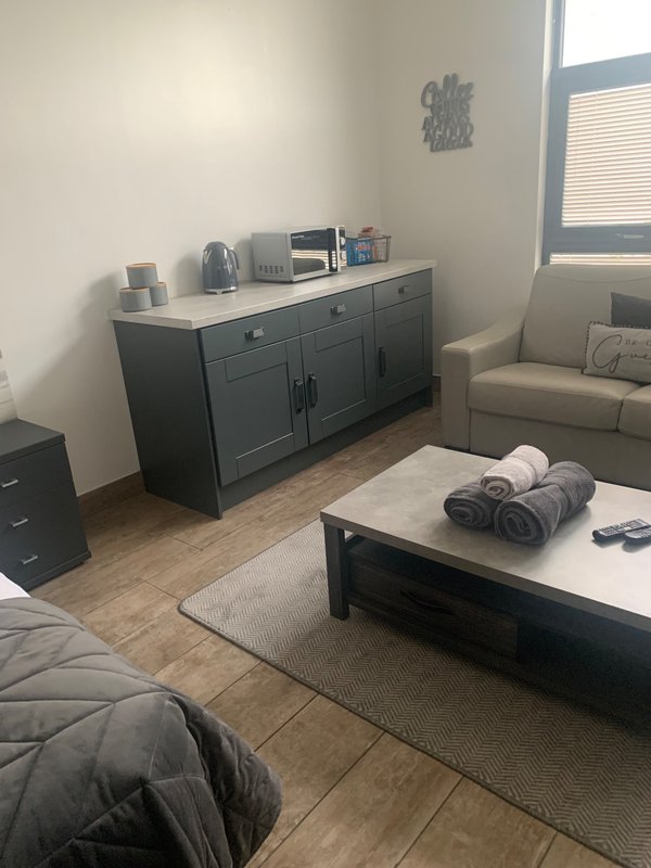 Living room with dark sideboard, cream armchair, coffee table with rolled towels, and wood flooring