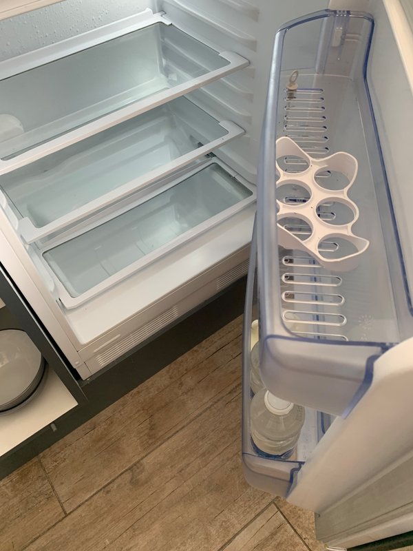 Open refrigerator with empty shelves and door compartments in kitchen