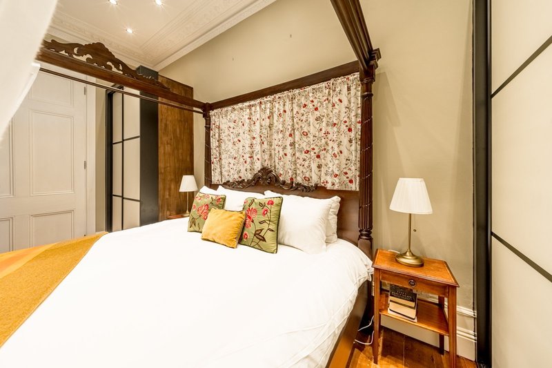 Bedroom with four-poster bed, white bedding, decorative pillows, wooden nightstands and lamps