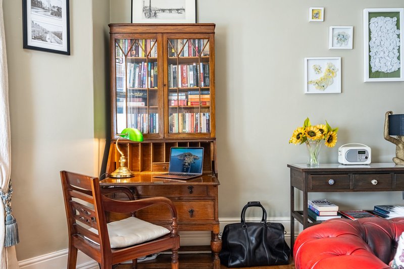 Home office with wooden desk, bookcase, chair, framed wall art and desk accessories