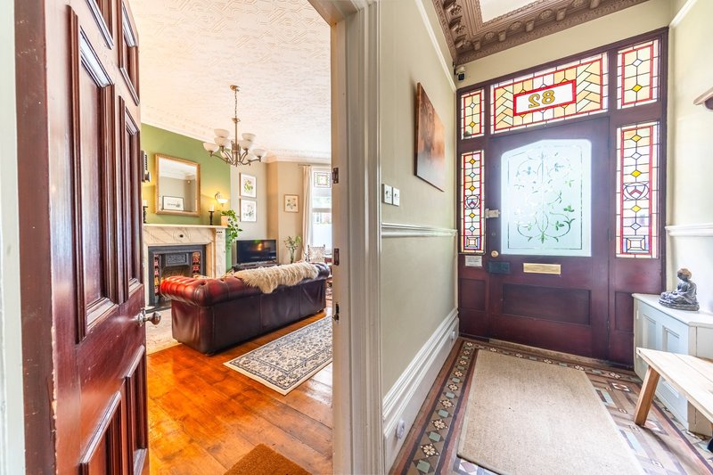 Hallway with hardwood floors, stained-glass window door, leading to living room with sofa