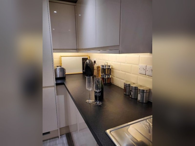 Modern kitchen with gray cabinets, black countertop, white subway tile backsplash and kitchen accessories