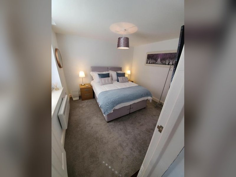 Bedroom with double bed, bedside lamps, pendant light, and grey carpet flooring