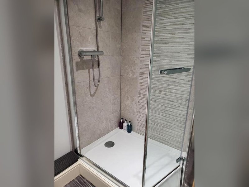 Modern shower enclosure with white tray, glass door, and wall-mounted fixtures
