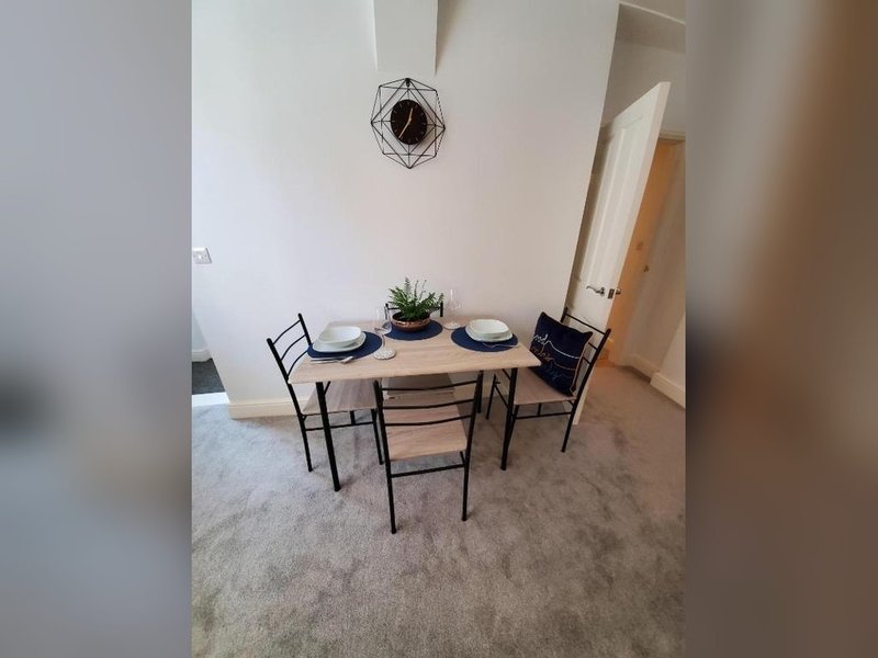 Dining area with wooden table, two chairs, place settings, and potted plant
