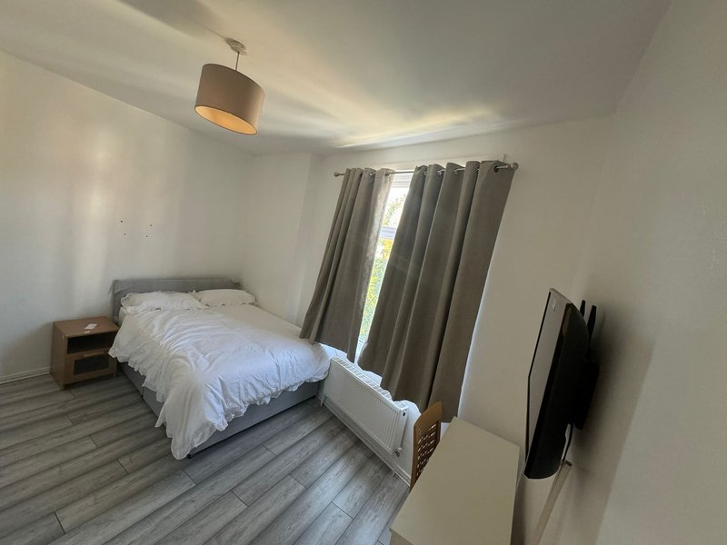 Bright bedroom with single bed, wooden nightstand, grey curtains and pendant light