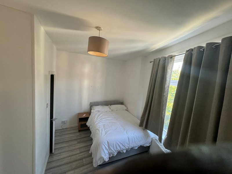 Bright bedroom with single bed, pendant ceiling lamp, and green curtains
