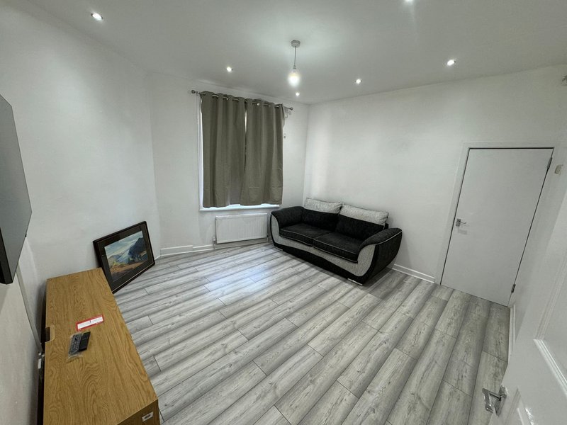 Modern living room with black sofa, wooden desk, striped flooring and window with curtains
