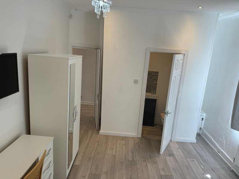 Modern bedroom with wooden flooring, wardrobe, multiple doors and crystal ceiling light