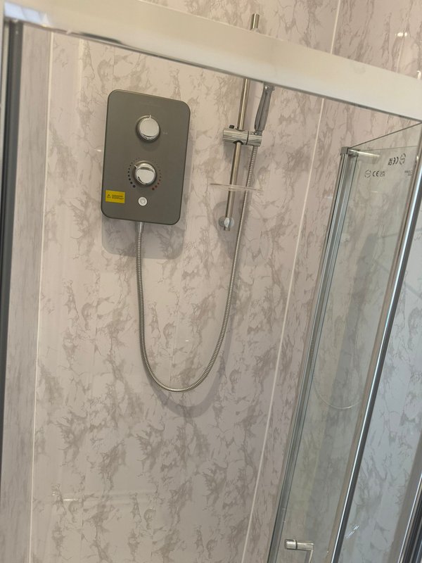 Modern bathroom shower cubicle with wall-mounted electric heater control panel