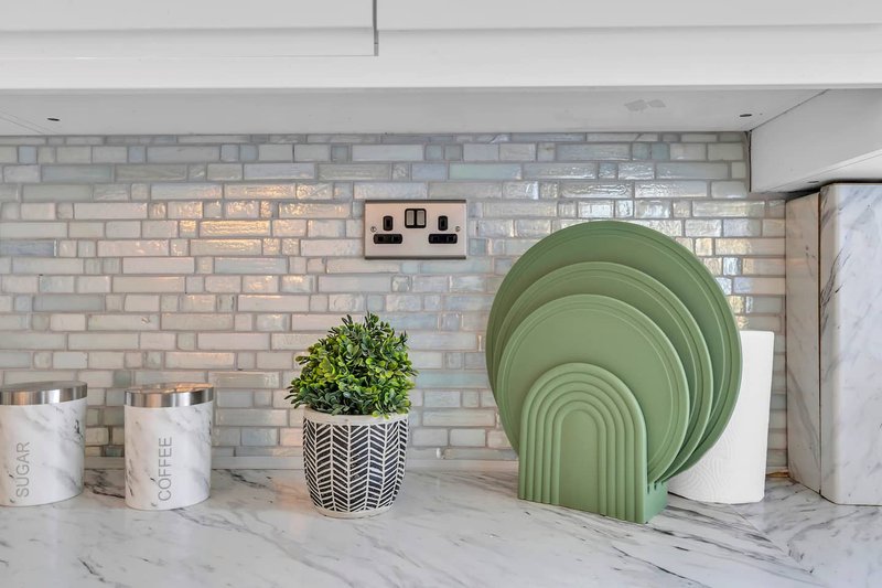 Kitchen counter with brick backsplash, decorative items, and white marble countertop