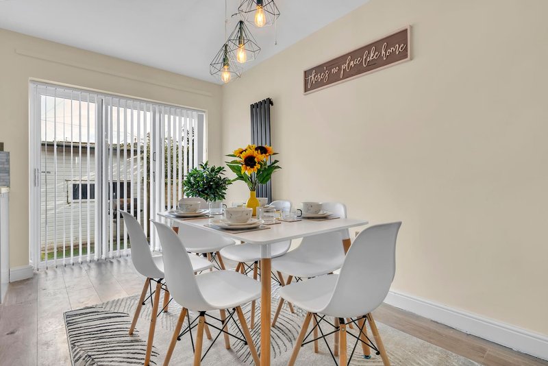 Dining area with round white table, modern chairs, sunflowers in vase, pendant lights