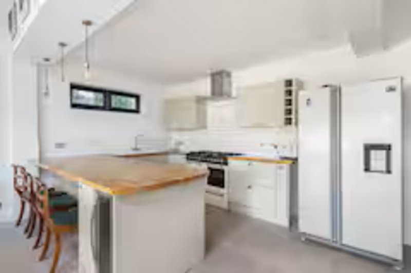 Modern kitchen with white cabinetry, wooden countertop island, stainless steel appliances and pendant lighting