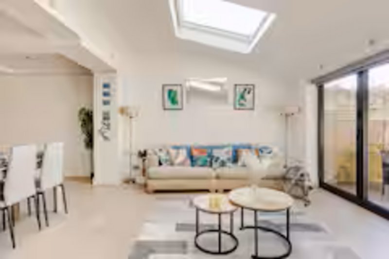 Bright open-plan living room with skylight, cream sofa, dining table and glass doors to garden