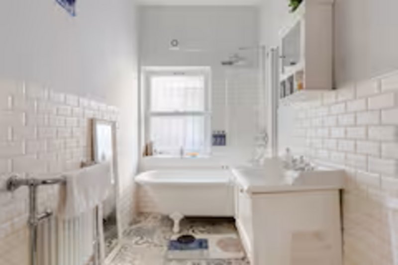 Clean bathroom with white subway tile, bathtub, sink, and window with natural light