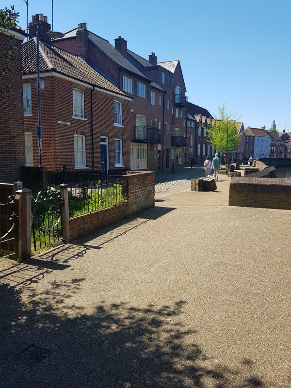 Red brick terraced houses with shared courtyard, iron railings and paved ground