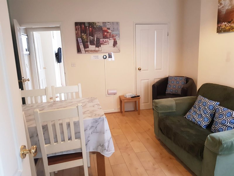 Living room with sofa, armchair, crib, wooden floor and framed wall art
