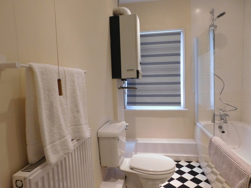 Bathroom with toilet, bathtub, sink, towel rail and black-and-white checkered floor