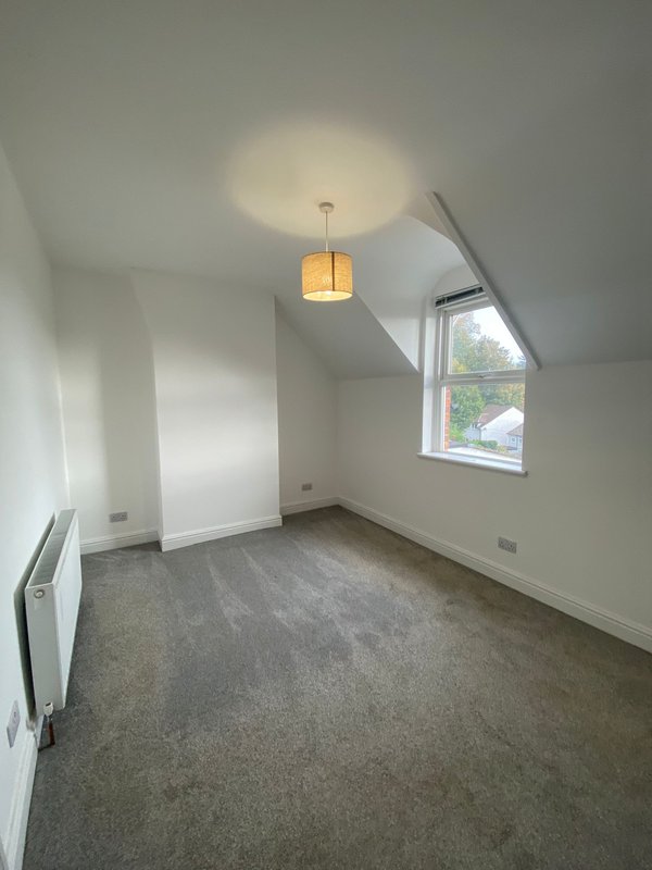 Bright attic bedroom with sloped ceiling, pendant light, carpet flooring and angled window