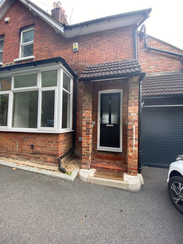 Red brick semi-detached house exterior with bay window, black door and driveway