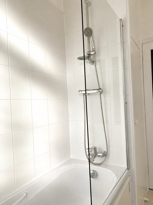 Clean white-tiled bathroom with shower enclosure, chrome fixtures and bathtub