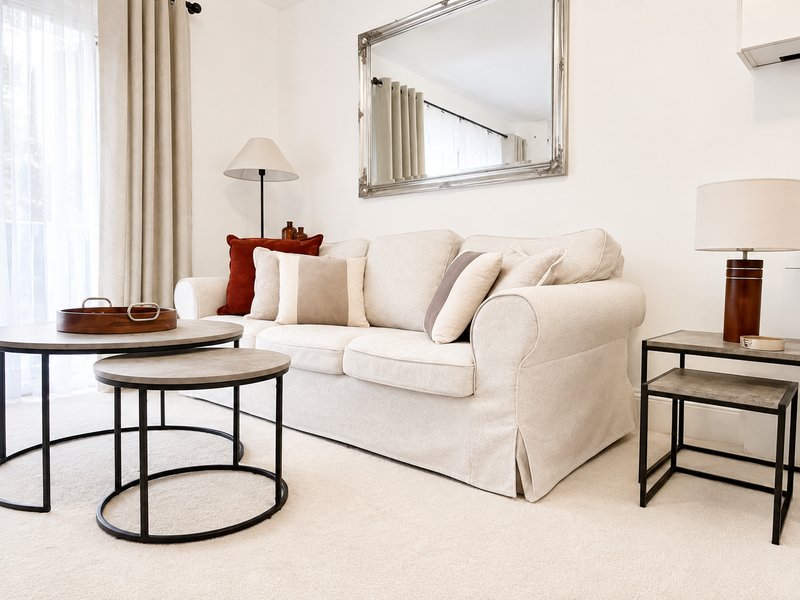 Modern living room with cream sofa, round nesting tables, mirror, and contemporary lighting