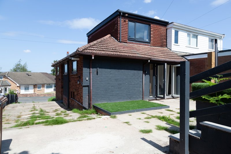 Modern brick house with dark garage door, large windows and front driveway