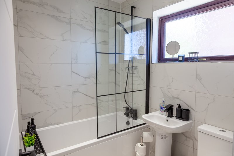 Modern bathroom with marble-effect tiles, glass shower enclosure, white sink and toilet