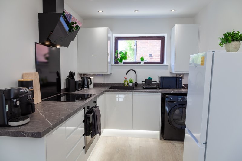 Modern kitchen with white cabinets, dark countertops, stainless steel appliances and window
