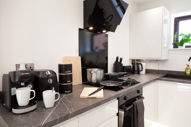 Modern kitchen with white cabinets, dark countertop, black appliances and coffee maker