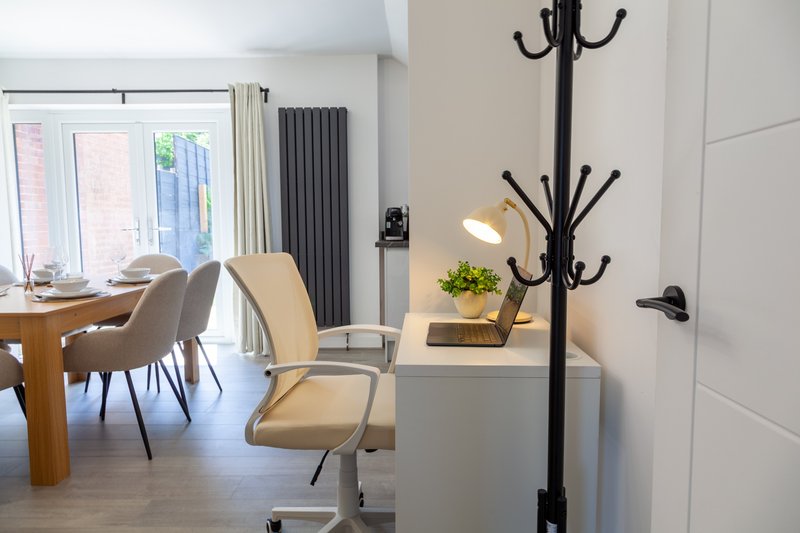 Modern open-plan living area with dining table, upholstered chairs, coat stand and radiator