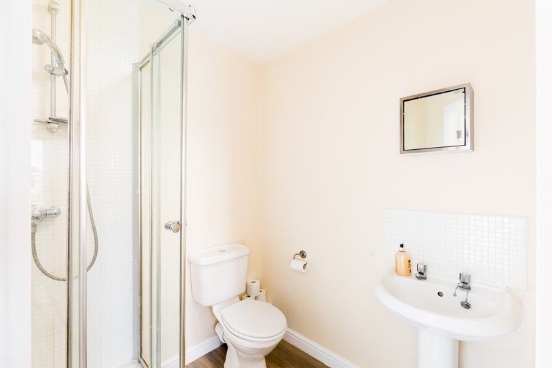 Clean modern bathroom with shower enclosure, toilet, pedestal sink and mirror