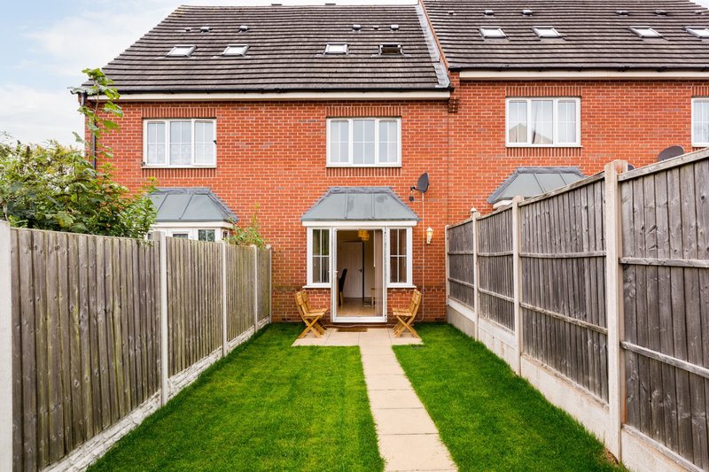 Brick townhouse with rear garden, patio, wooden fencing and manicured lawn