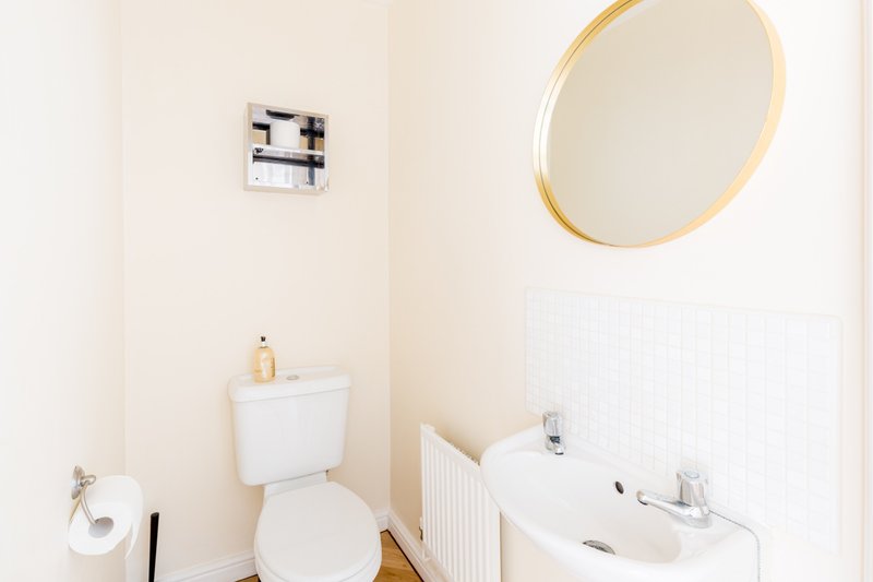 Clean bathroom with toilet, white sink, gold-framed mirror and radiator