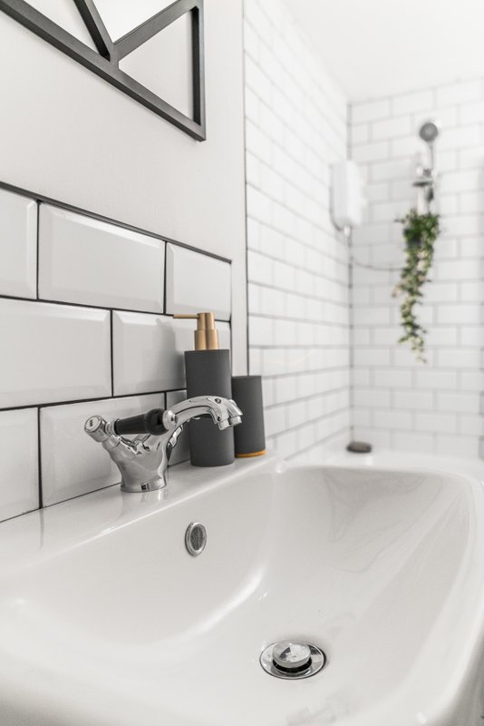 Modern bathroom sink with white subway tiles, black-framed mirror, and bathroom accessories