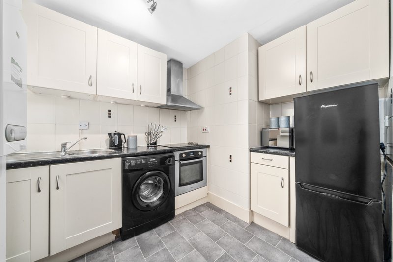 Modern kitchen with white cabinetry, black appliances, washing machine and black refrigerator