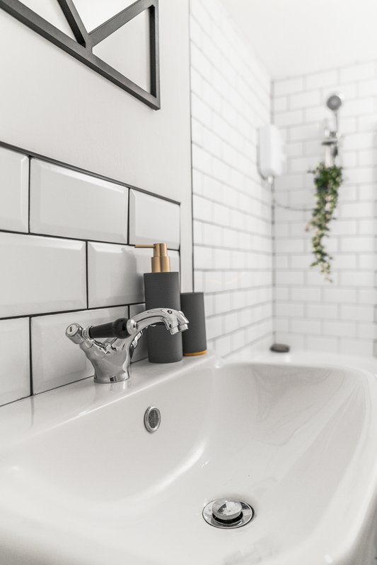 Modern bathroom sink with white subway tiles, chrome faucet, and potted plant decor